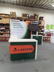 Custom Inline with SuperNova Backlit Fabric Graphic, Wood Frame, Monitor Mount with Graphic Support Panels, Backlit Logos, Backwall Counter with RGB LED Accent Lights, and L-Shaped Counter with Backlit Logo, RGB LED Accent Lights, and Locking Storage -- V